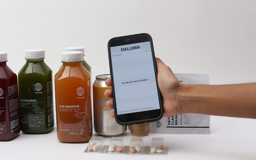 Hand hält Smartphone mit DALUMA Health Coach vor Saftflaschen