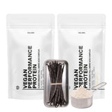 Zwei weiße, wiederverschließbare Beutel mit der Aufschrift VEGANES PERFORMANCE PROTEIN VANILLE DOUBLE von DALUMA stehen hinter einem Metalltablett mit Vanilleschoten und einem mit Vanilleproteinpulver gefüllten Messbecher.