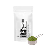 Ein weißer Beutel mit der Aufschrift DALUMA VEGANES PERFORMANCE PROTEIN NEUTRAL steht aufrecht neben einem Metallportionierer mit grünem Pulver. Die minimalistische Verpackung mit schwarzem Text auf weißem Grund hebt den neutralen Geschmack hervor.