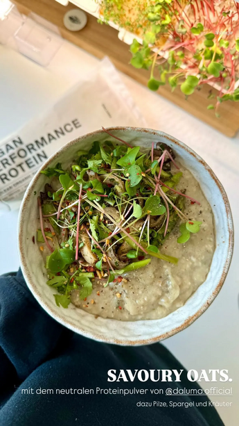 Eine Schüssel mit cremigen, schmackhaften Haferflocken, belegt mit Mikrogrün und Kräutern, mit Pilzen und Spargel. Im Hintergrund sieht man ein Paket mit der Aufschrift "Urban Performance Protein" und frisches Grün auf einem Tablett. Der Text lautet "SAVOURY OATS".