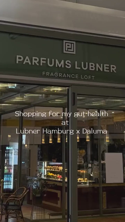 Schaufenster von Parfums Lubner Fragrance Loft mit Glastüren und warmer Innenbeleuchtung. Der überlagerte Text lautet: Einkaufen für meine Darmgesundheit bei Lubner Hamburg x Daluma.