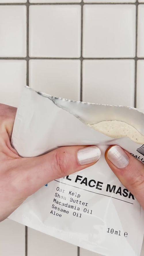 Eine Hand mit weiß lackierten Nägeln hält eine teilweise geöffnete weiße Packung dailumade.comEP HYDRATION FEUCHTIGKEITSMASKE, in der eine cremefarbene beigefarbene Maske zum Vorschein kommt.