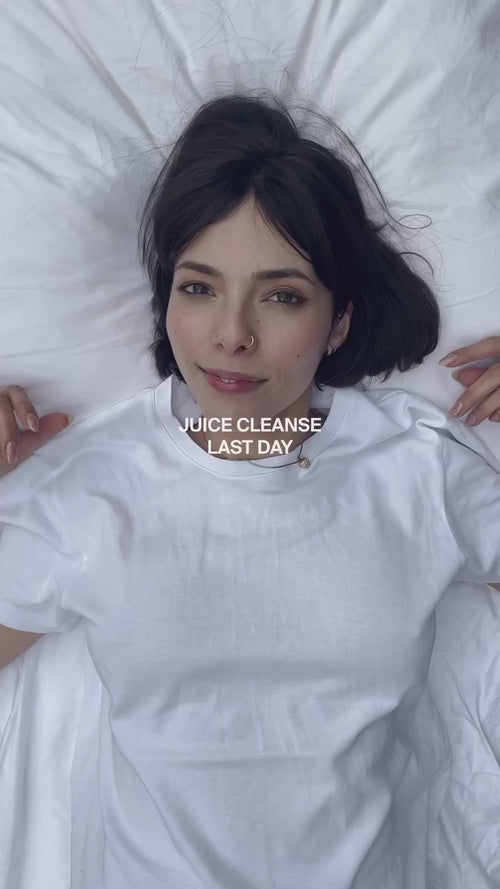 Eine Frau mit dunklem Haar liegt auf einem weißen Bett und trägt ein weißes T-Shirt. Der Text auf dem Bild lautet JUICE CLEANSE LAST DAY. Sie blickt mit einem leichten Lächeln in die Kamera.